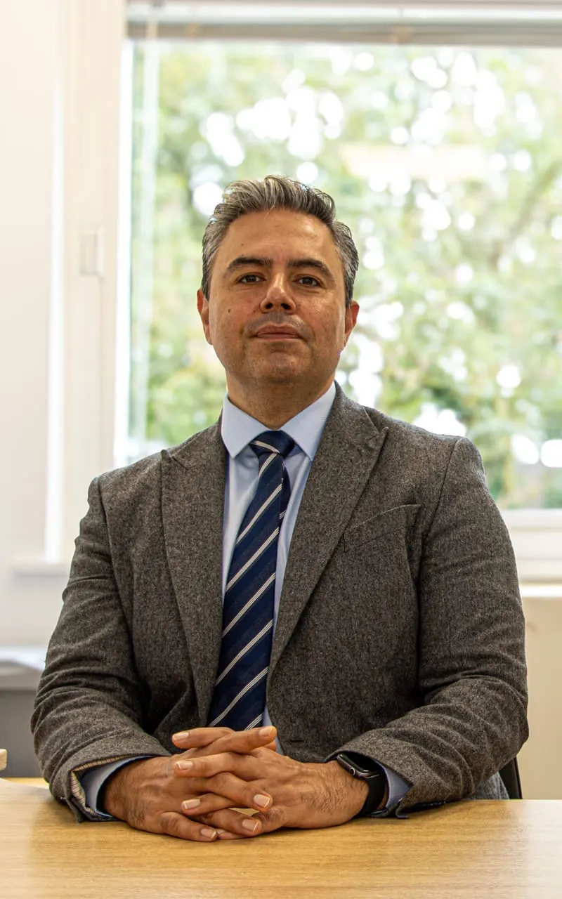 Mr Najib Daulatzai, colorectal and general surgeon in London and Hertfordshire, seated at his desk in professional attire
